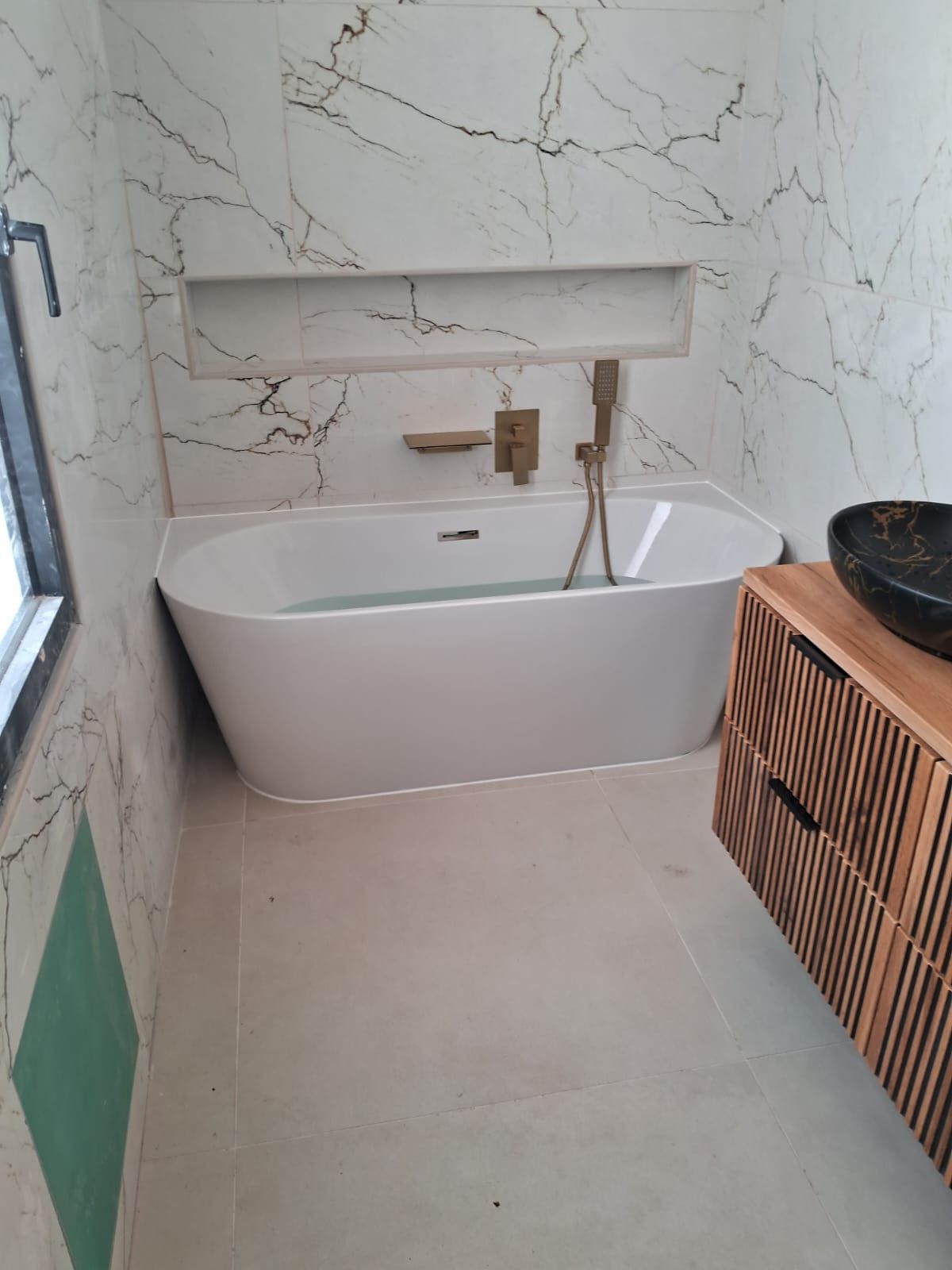 Salle de bain entièrement rénovée par PRO-REFLEX : baignoire îlot et faïence effet marbre